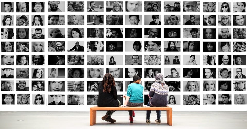 3-people-sitting-in-front-of-a-wall-of-pictures-of-people